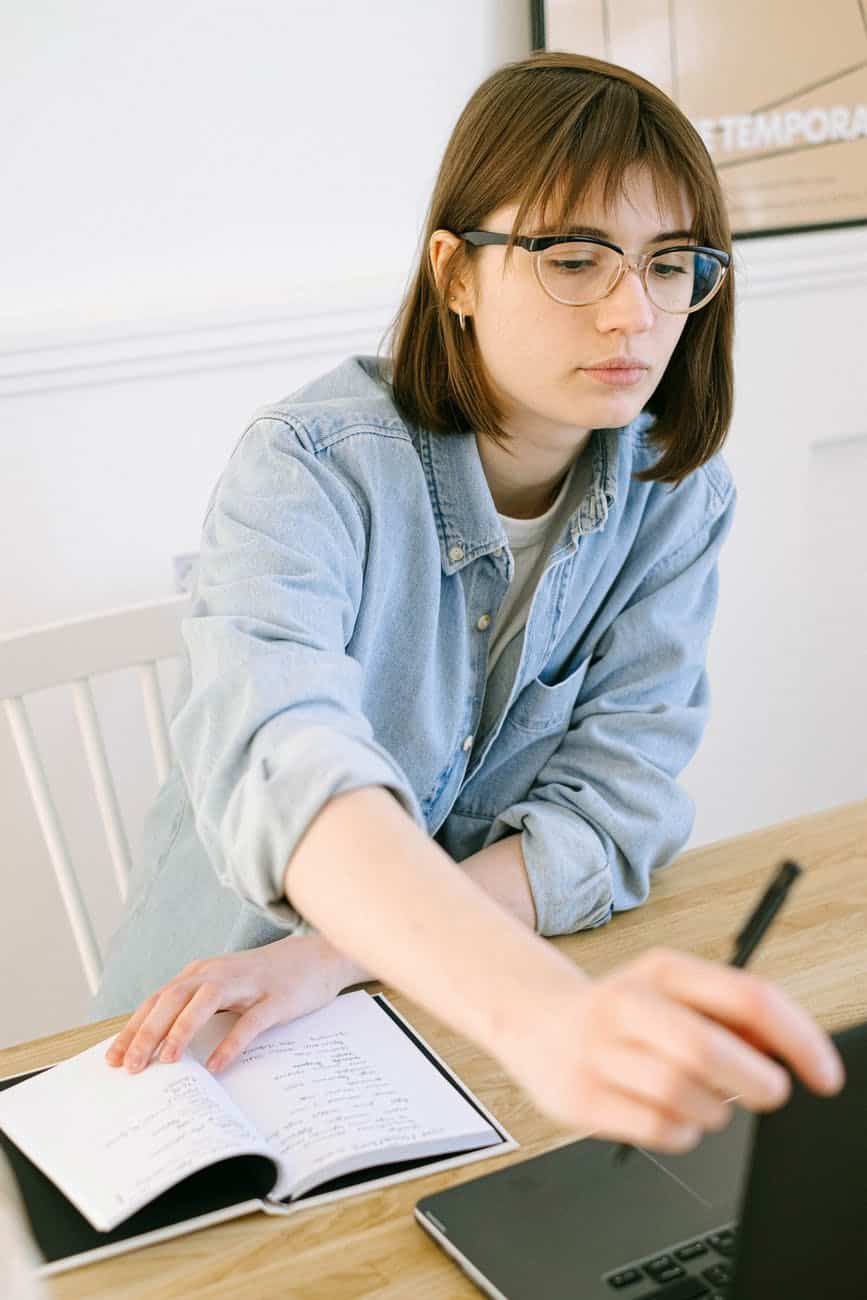 woman looking at a laptop and taking notes