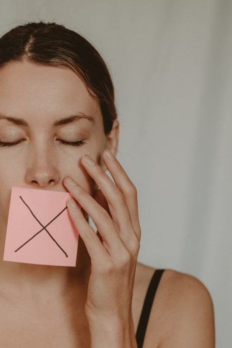 woman with cross symbol on mouth unable to speak