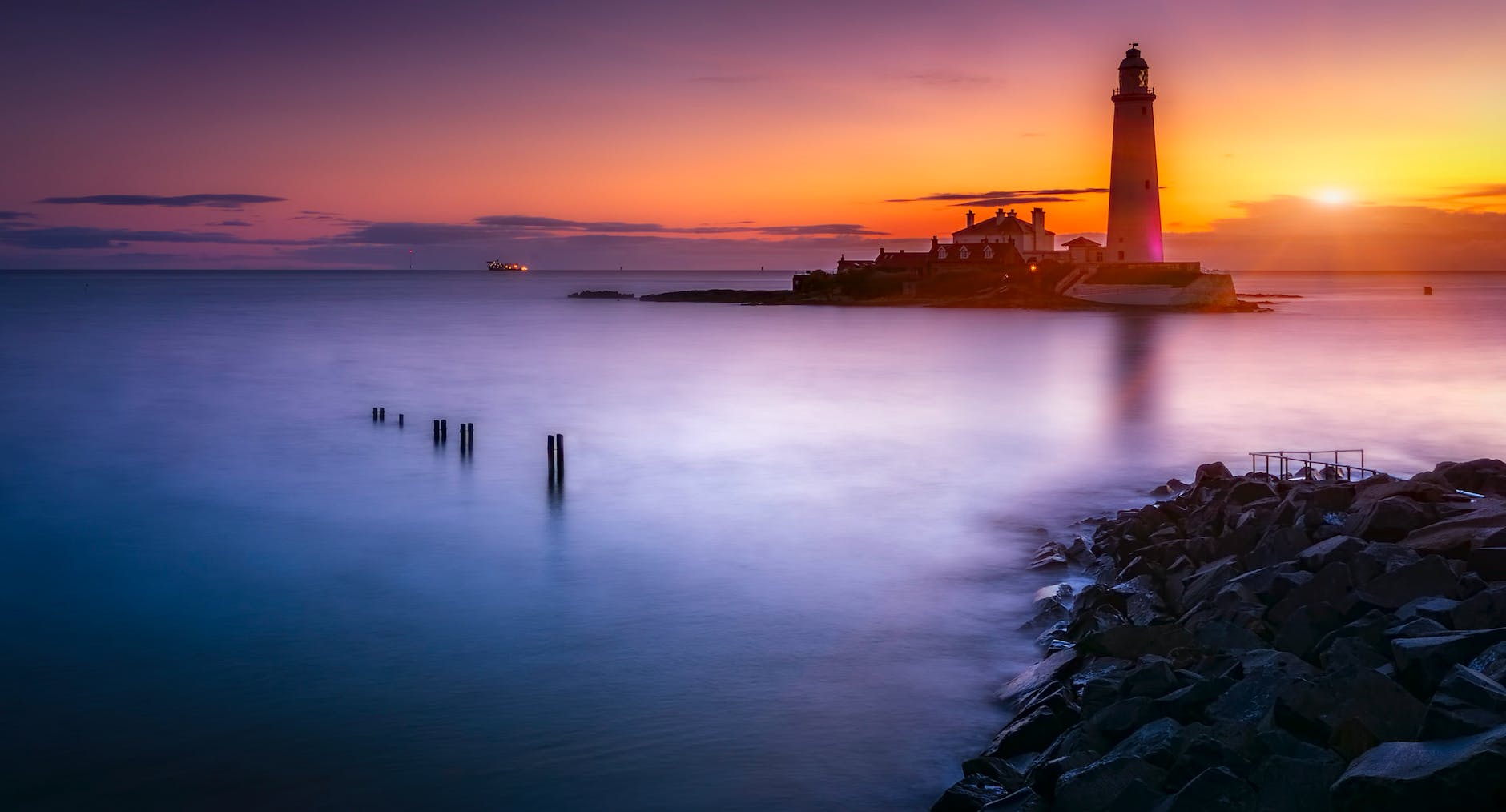 lighthouse on island under orange sunset
